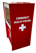 Red community health station with a white cross symbol on a paved surface.